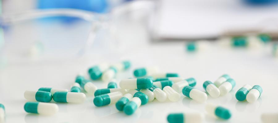 Prescription Drug Pricing. Green and white capsules on a pharmacy counter.